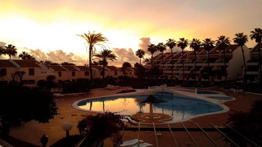 a resort pool with a sunset in the background at Cool Duplex in Playa las Americas in Playa de las Americas