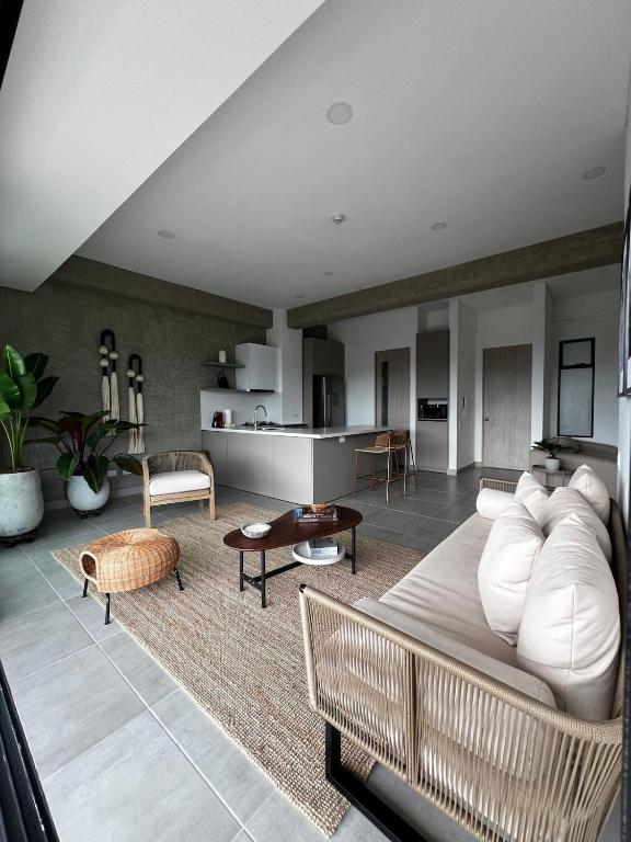 a living room with a white couch and a kitchen at Tropicalia Home - Apartment in Armenia