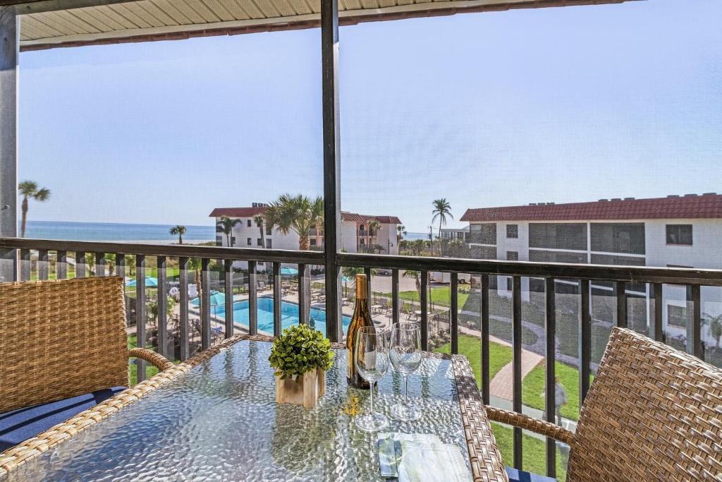 a table with wine glasses on a balcony with the ocean at 3rd Floor Sanibel Condo With Balcony And Beach Views 4B3 in Sanibel