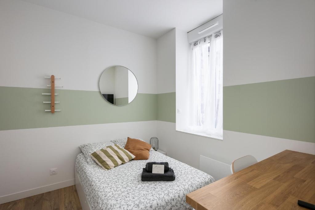 Cette chambre blanche comprend un lit et une table en bois. dans l'établissement Le Vigilant, à Brest
