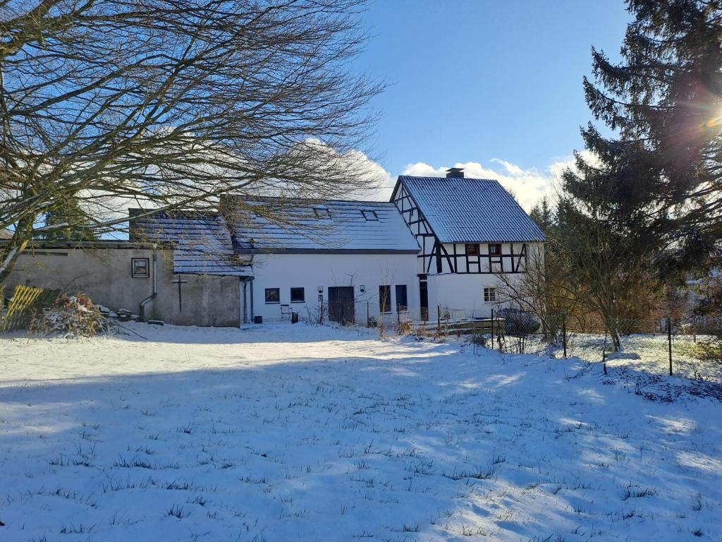 a white barn with snow on the ground at Haus Burg, Ferienhaus in Bongard