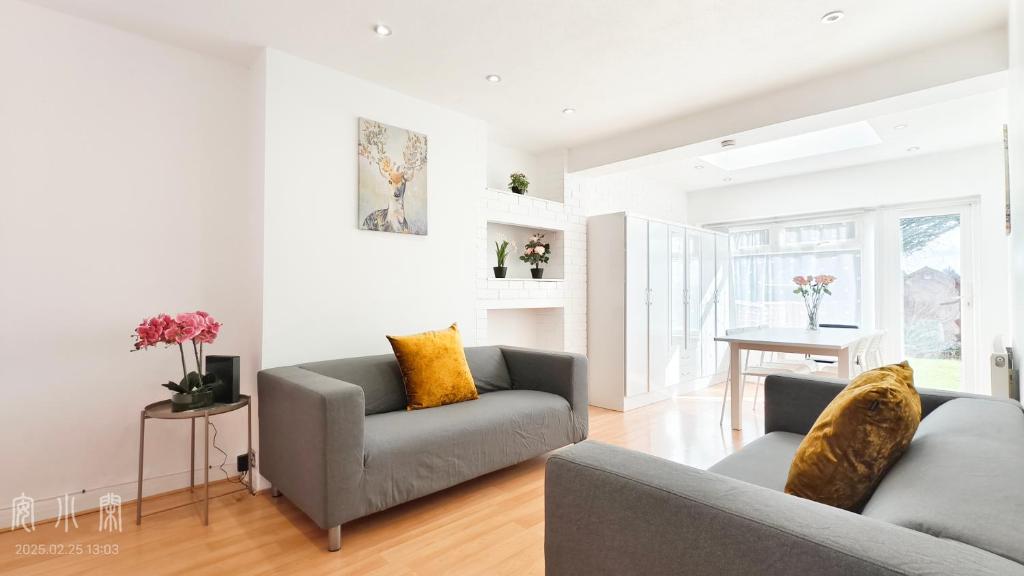 a living room with two couches and a table at The Fairway Garden in South Ruislip Station