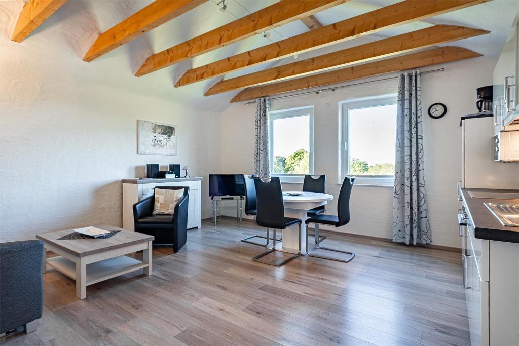 a kitchen and living room with a table and chairs at Ferienwohnung Ebbe mit Loggia und schönem Ausblick am Badesee Tannenhausen in Aurich