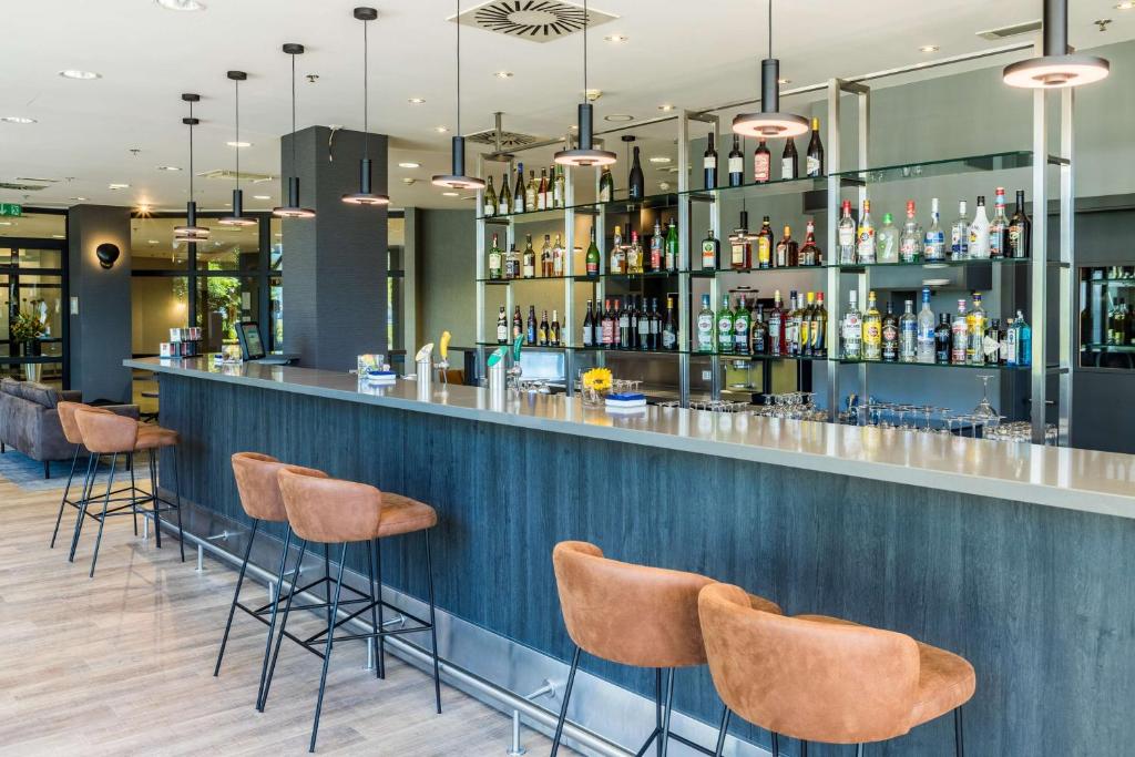 a bar in a restaurant with stools at NH Luxembourg Airport in Luxembourg