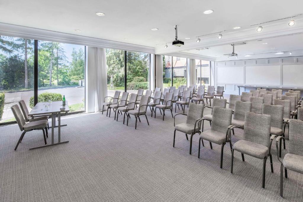 a conference room with chairs and tables and windows at NH Luxembourg Airport in Luxembourg