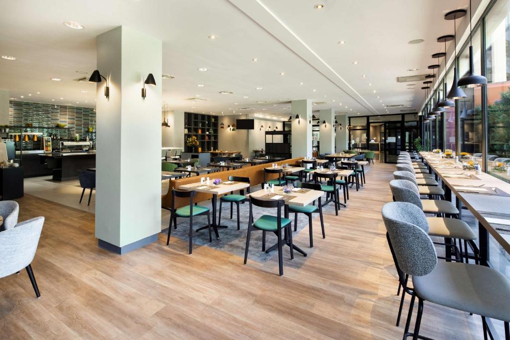 a restaurant with tables and chairs and a bar at NH Luxembourg Airport in Luxembourg