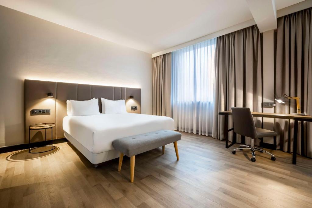 a hotel room with a white bed and a desk at NH Luxembourg Airport in Luxembourg