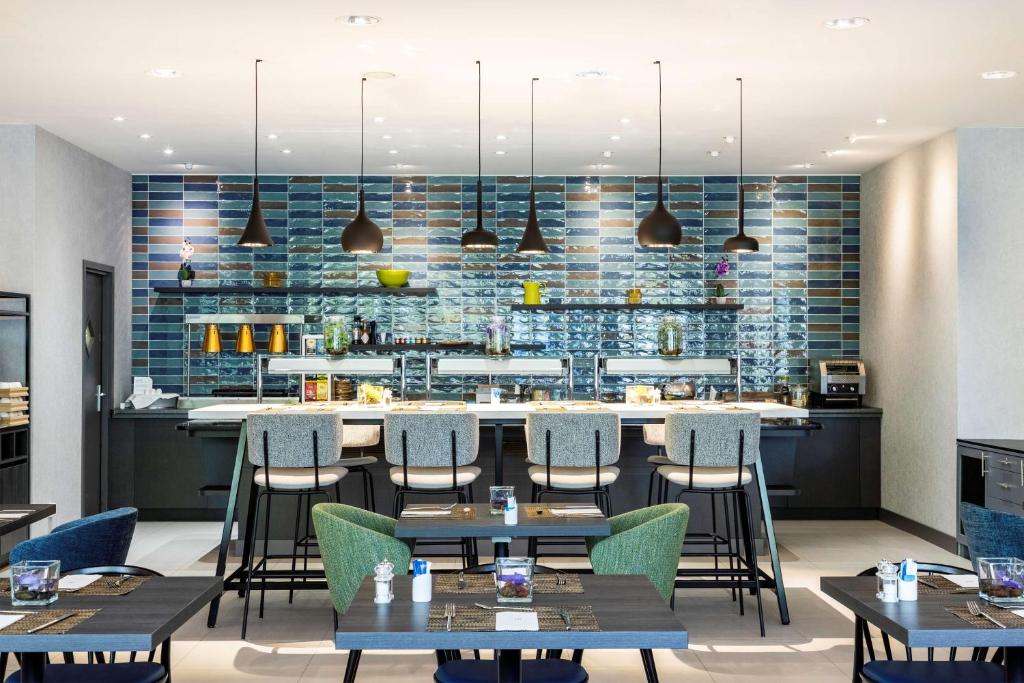 a restaurant with tables and chairs and a bar at NH Luxembourg Airport in Luxembourg