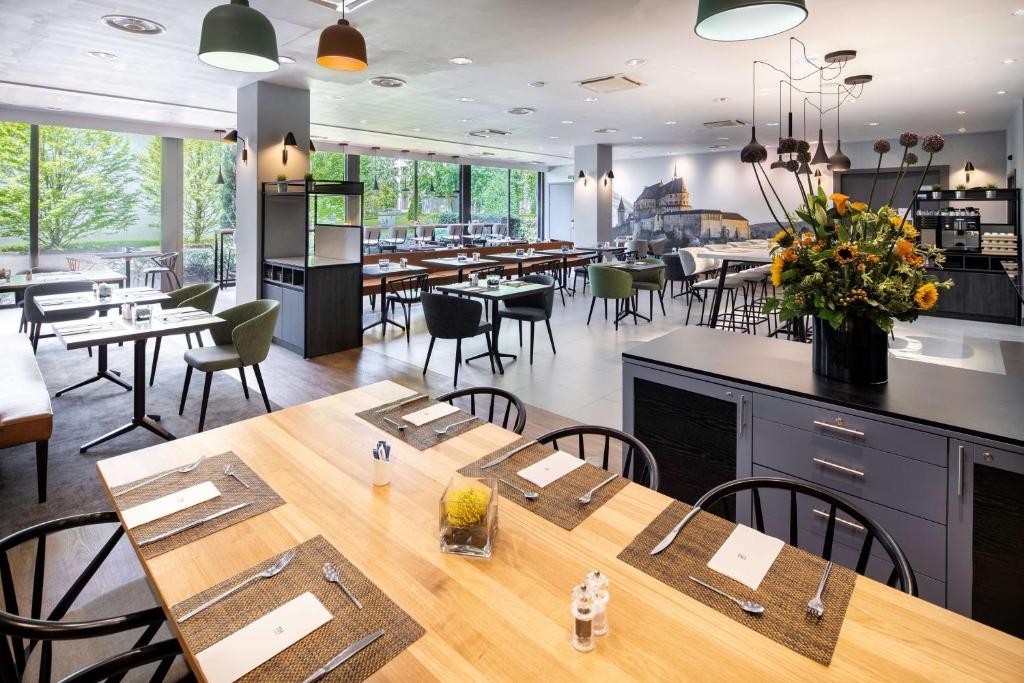 a restaurant with tables and chairs and a cafeteria at NH Luxembourg Airport in Luxembourg