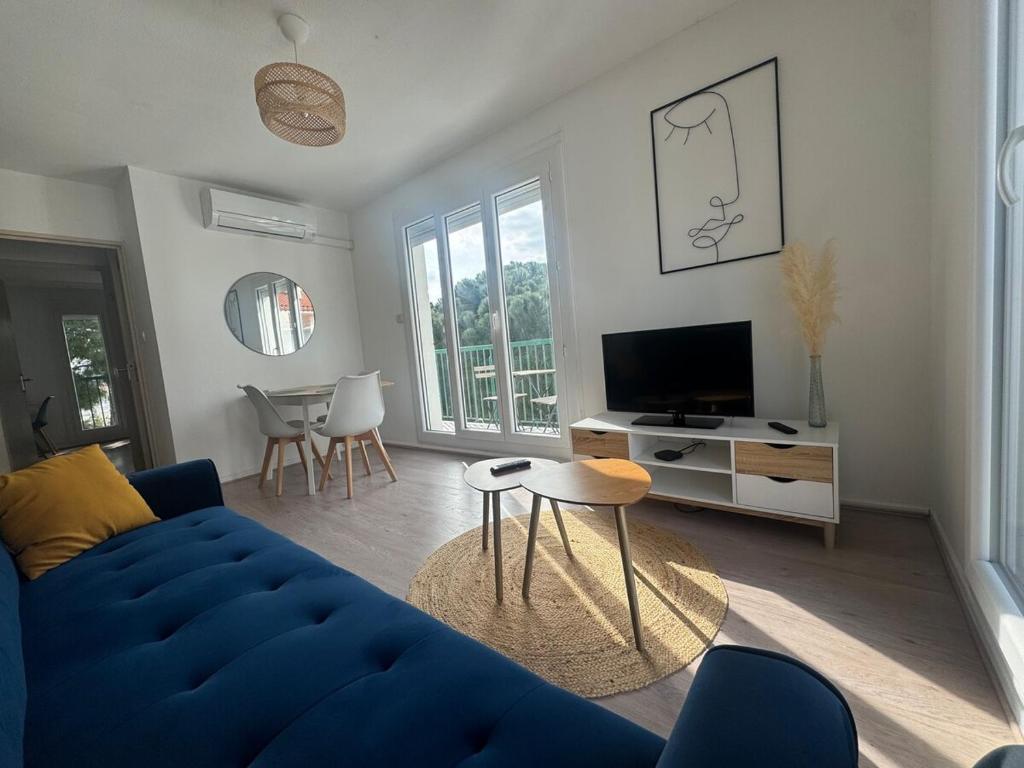 un salon avec un canapé bleu et une télévision dans l'établissement La Belle Escale à Perpignan, à Perpignan
