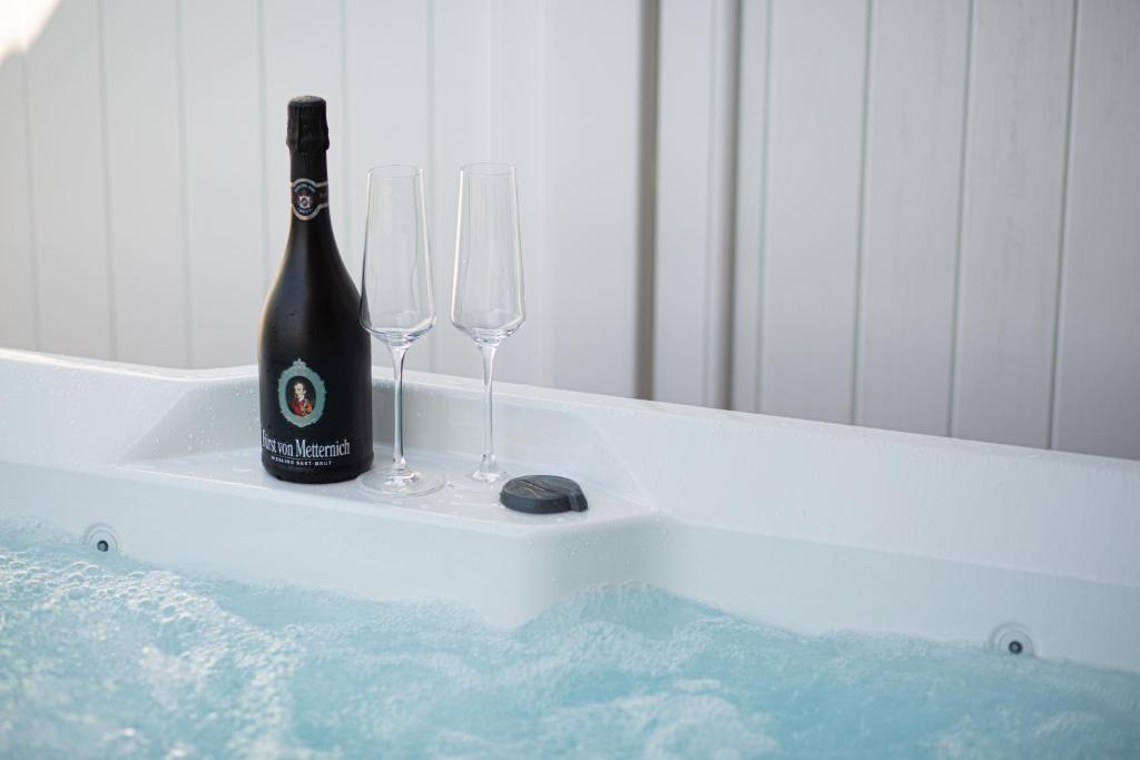 una bottiglia di champagne e 2 bicchieri di vino in una vasca da bagno di Wellness-Doppelhaushälfte "Sand" eingezäunt 130m a Fehmarn