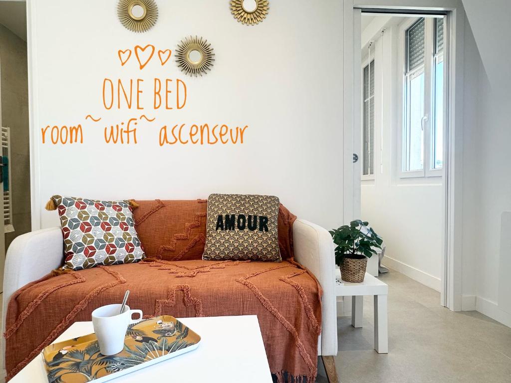 une chambre avec un lit avec un couvre-lit orange et une table dans l'établissement Beautiful & cosy appart, calme et lumineux, à Nice