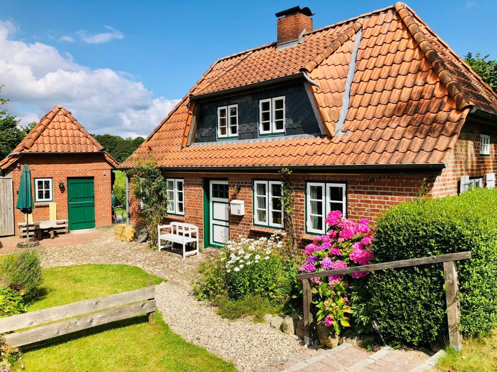 a small brick house with a garden and flowers at Tante Kamps Hus - Uriges Häuschen mit Garten und Geschichte in Bönstrup