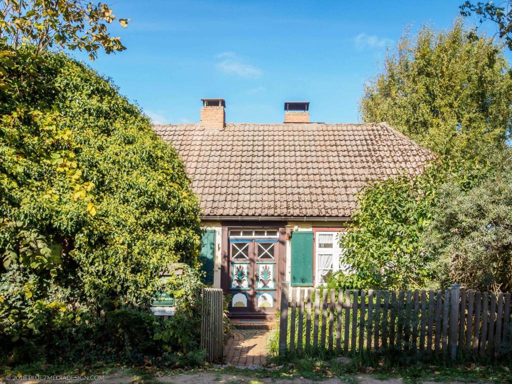 una pequeña casa verde con una valla de madera en altes Kapitänshäuschen, en Prerow
