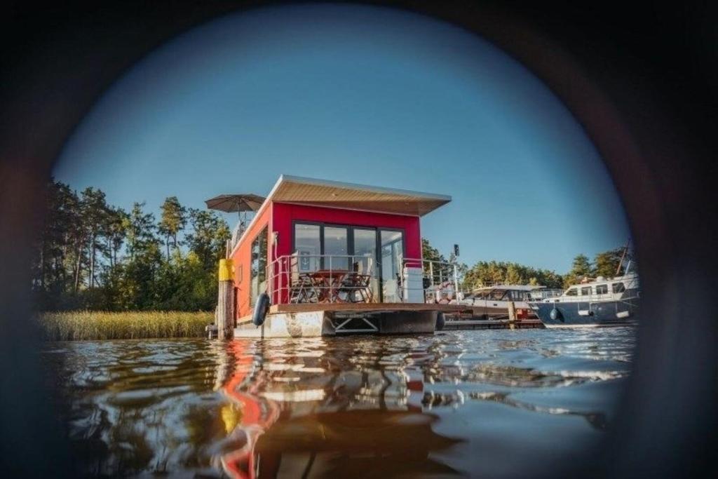 a small house on a dock on a body of water at Hausboot Enola in Fürstenberg-Havel
