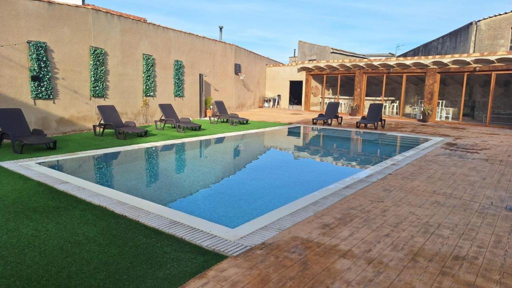 a swimming pool in a yard with chairs next to a building at Casa Rural 3 Suspiros in Torre de Santa María