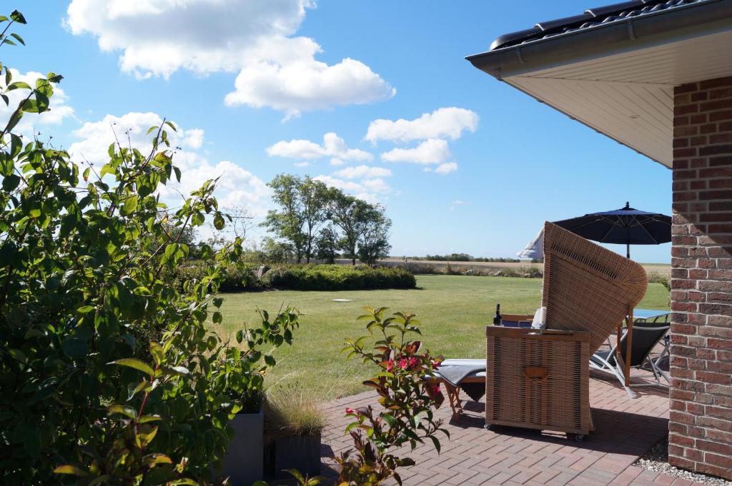 une terrasse avec une chaise, un parasol et un champ dans l'établissement Ferienhaus Ankerplatz FH2, à Fehmarn