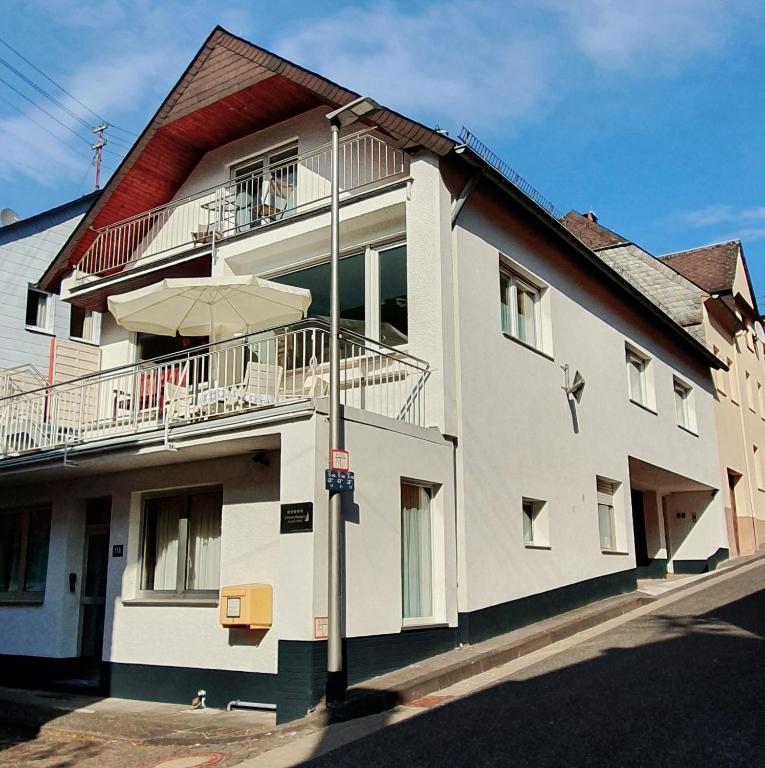 a white building with a balcony and an umbrella at Ferienwohnung an der Mosel, Julia in Senheim