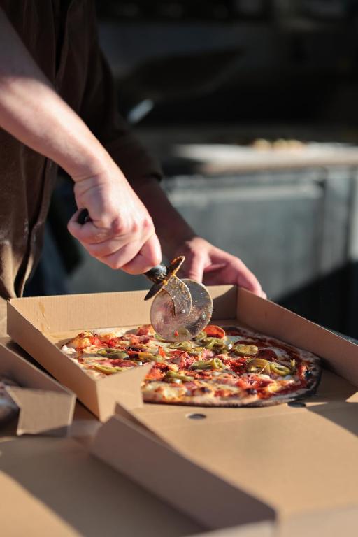 a person cutting a pizza with a pizza cutter at The Red Lion Inn Alnmouth in Alnmouth
