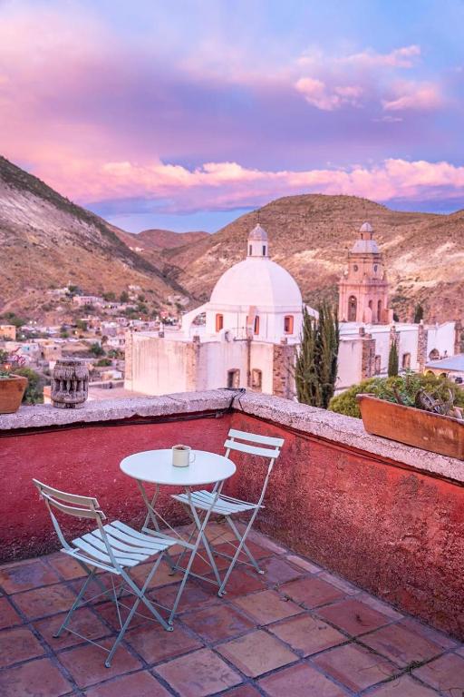 a table and chairs on a balcony with a view of a city at Casa Sulahue in Real de Catorce