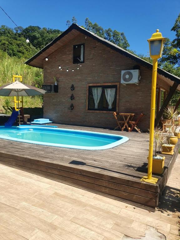 a swimming pool on a wooden deck next to a house at Canto do Beija-flor Rolante RS in Rolante