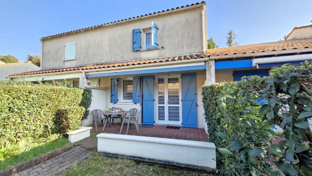 une maison avec une porte bleue et une table dans l'établissement Meschers sur Gironde - PETITE VILLA pour un SEJOUR EN FAMILLE en RESIDENCE, à Meschers-sur-Gironde