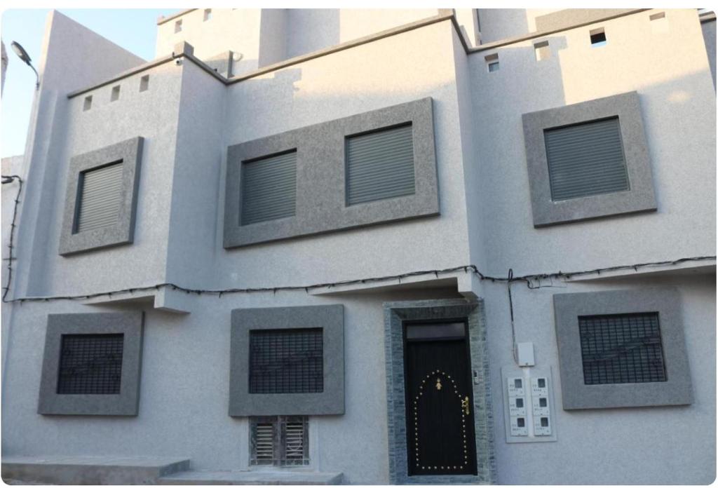 ein großes weißes Gebäude mit einer schwarzen Tür in der Unterkunft Tiwaline Tarsime App D in Sidi Ifni