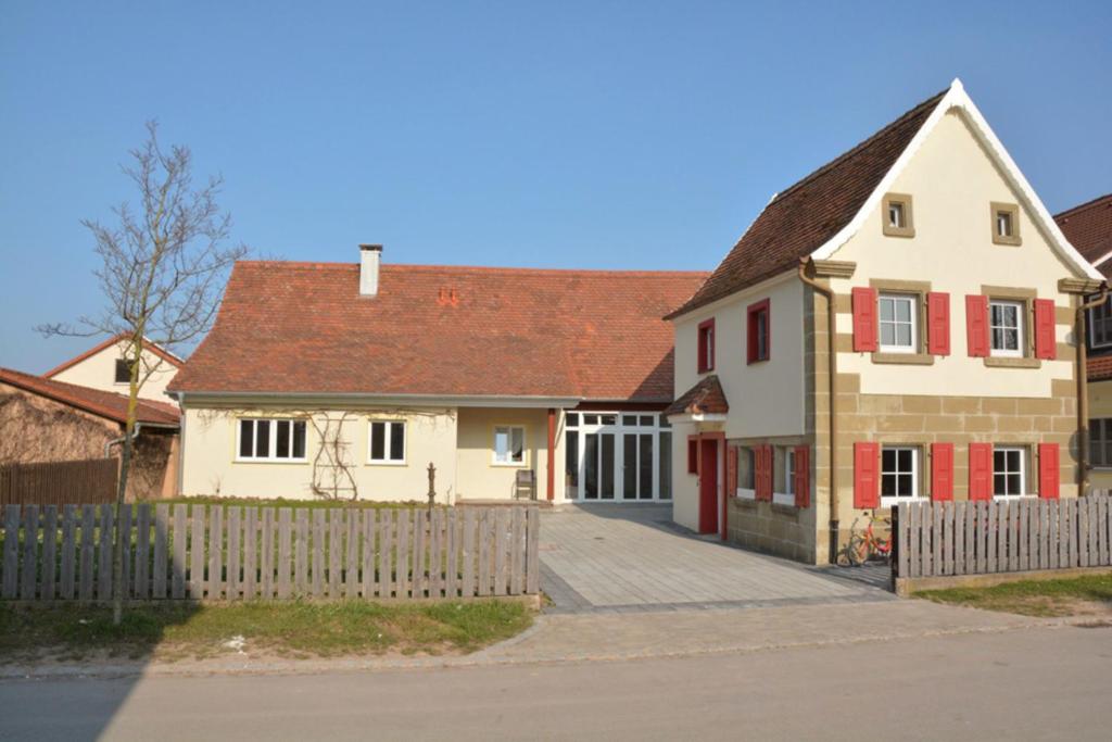 a white house with red doors and a fence at Haus Kornblume in Colmberg