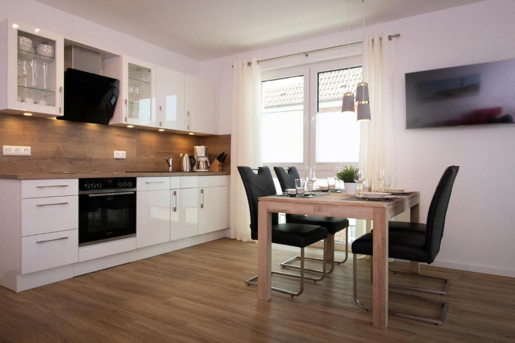 a kitchen with a wooden table and chairs and a dining room at FeWo Dünenquartier Cuxhaven - ideal für Familien und Paare in Cuxhaven