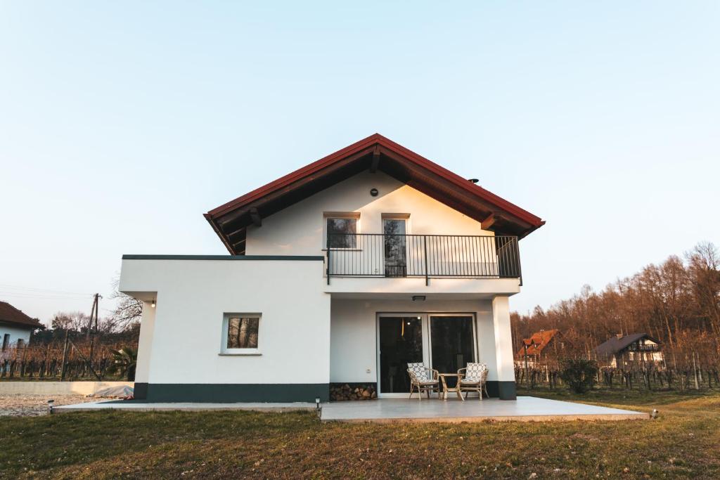 a white house with a balcony and two chairs at Zelena harmonija in Moravske Toplice