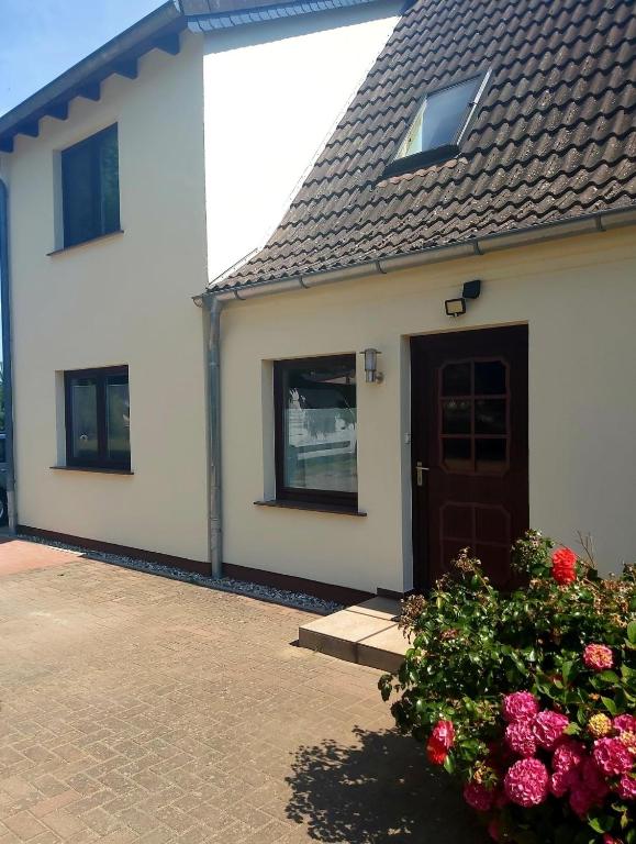 a white house with a door and some flowers at Ferienwohnung in Gresenhorst