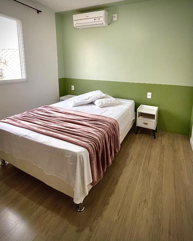 a bed in a room with a green wall at Ap de 2 quartos com AR, wifi e garagem - Bairro tranquilo in Santo Ângelo