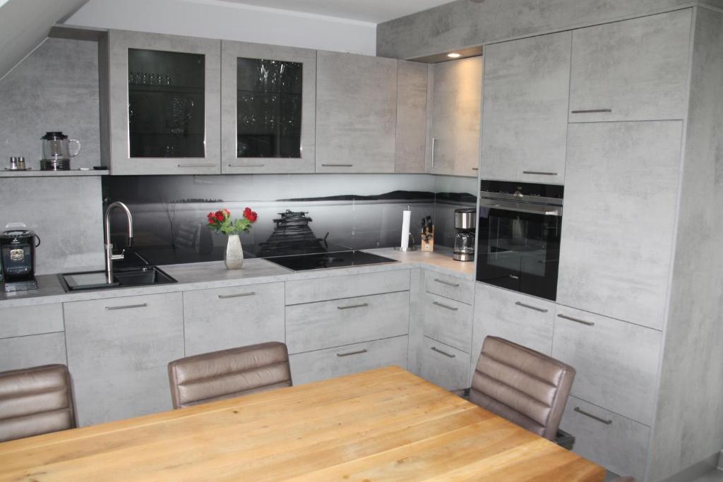 a kitchen with a wooden table and chairs in it at Seeblick 8 - Luxus direkt am Hafen von Norddeich in Norddeich