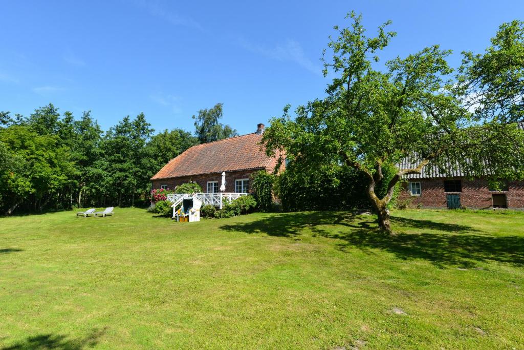 a house with a tree in front of a yard at Michels Huus - Schloss Gelting in Gelting