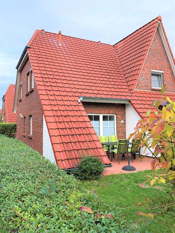 a house with a red roof with a patio at Dat Onnens Hus - Burhave 16 in Butjadingen