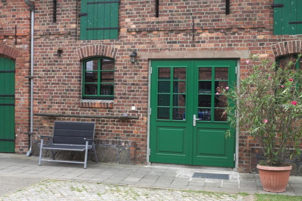 a green door and a bench in front of a brick building at Spreewälder Schwalbenhof - Ferienwohnung "Nistkasten" in Golßen