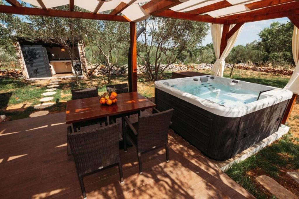 a patio with a hot tub and a table at House Stone house with jacuzzi in Lukoran