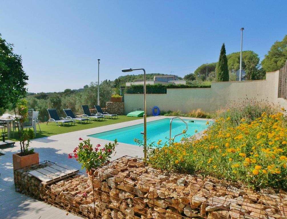 a swimming pool in a yard with a stone wall at Ca la Moni Gualta in Gualta