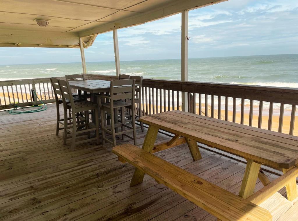a wooden deck with a table and chairs on the beach at Cozy Cottage in Flagler Beach