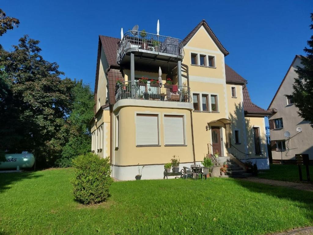 a yellow house with a balcony on top of it at Ferienwohnung Ehrich in Stöbnitz