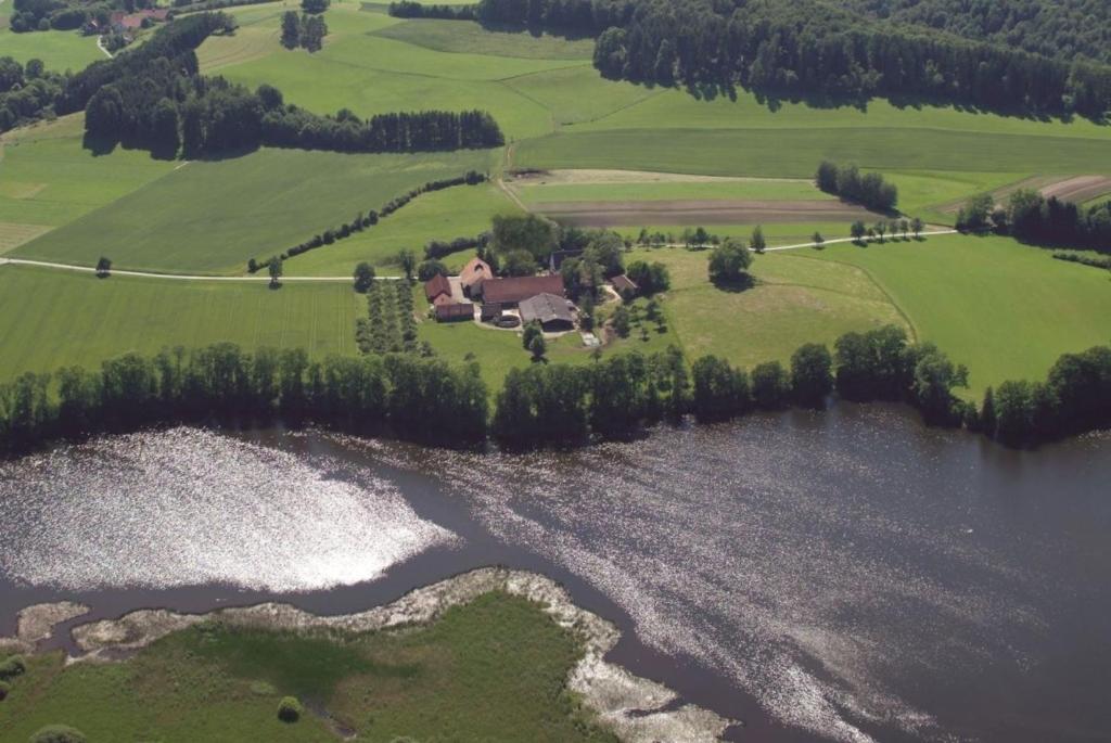 an aerial view of a house next to a lake at Rösslerhof Ferienwohnung Rösslerweiher in Schlier-Unterankenreute