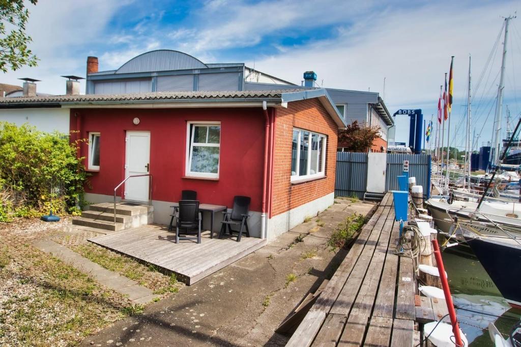 a small red house with a wooden deck next to a boat at Alte Segelschule in Lübeck