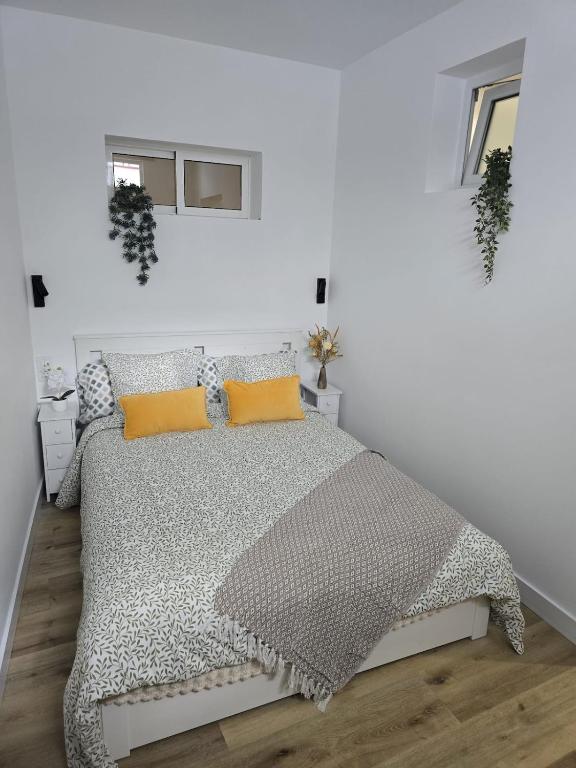 a white bedroom with a large bed with orange pillows at Apartamento Teror Encantado in Teror