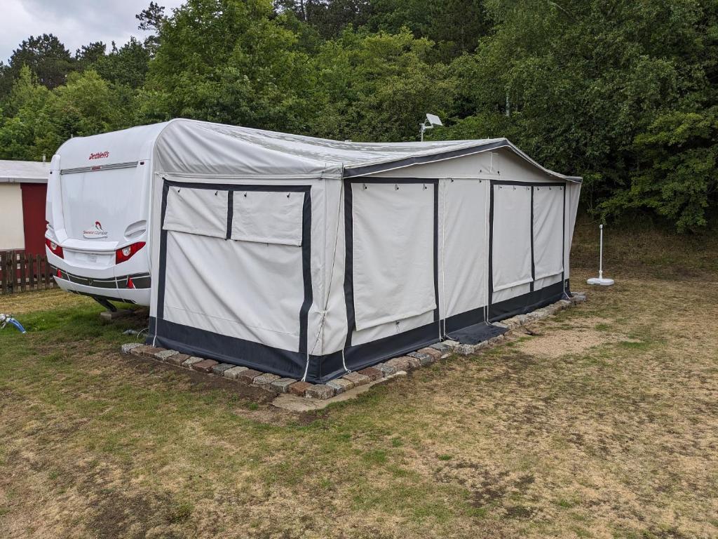 a camper tent sitting in a field next to a truck at Luxuswohnwagen Karpfen am Kransburger See 354 in Kransburg