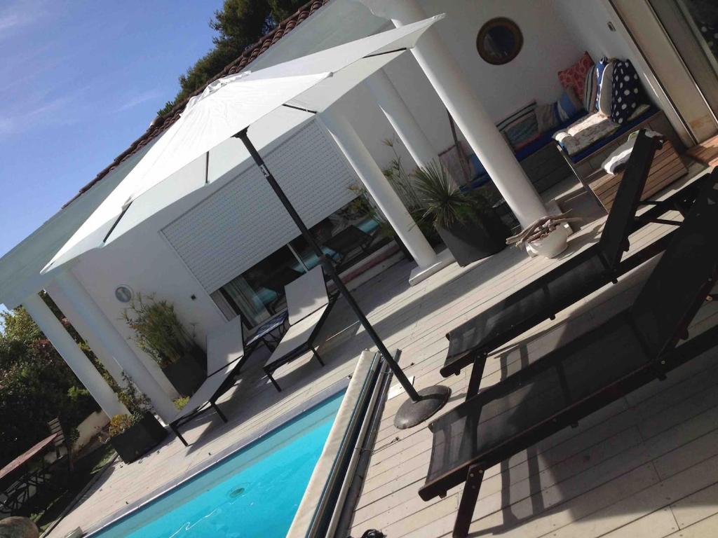 une maison avec une piscine et un parasol dans l'établissement villa near sea, heated pool,Isolella,Corsica, à Pietrosella