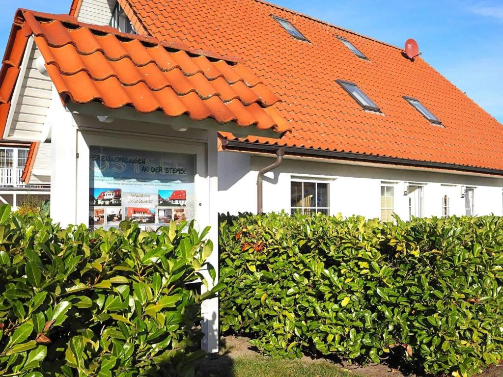 an orange roof on a house with a hedge at FeWo "Stems - W5" in Prerow