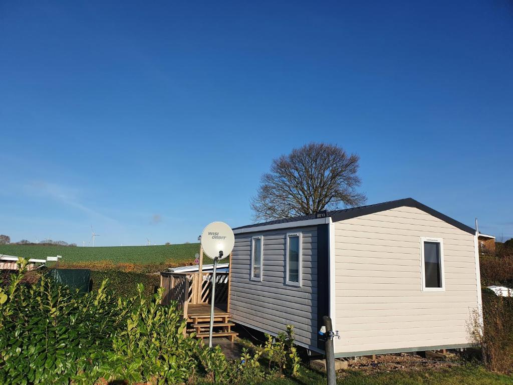a tiny house with a satellite in a field at Campingland Ostsee - Mobilheim 016Weitsicht in Schashagen