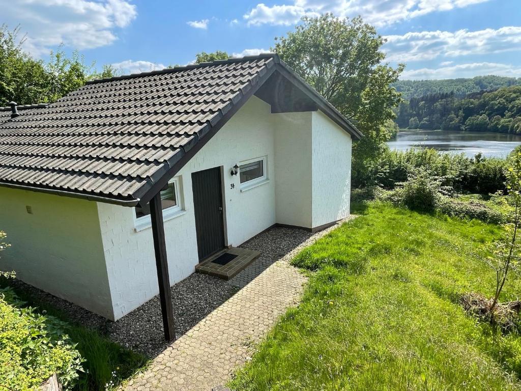 a small white building with a door in the grass at Landhaus am See 934 in Biersdorf