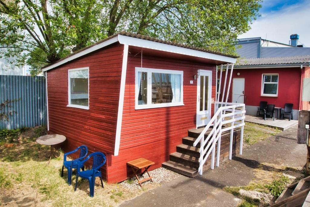 a red and white tiny house with blue chairs at Finnenhaus 1 in Lübeck