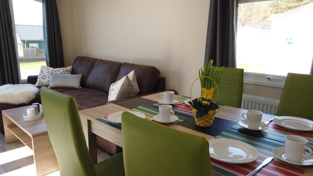 a dining room with a table and green chairs at Chalet Austernfischer am Kransburger See 547 in Kransburg